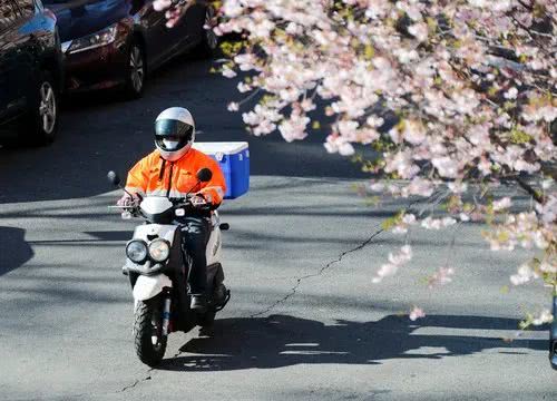 4月1日,在美国纽约,戴口罩的快递员骑车经过一处居民区.